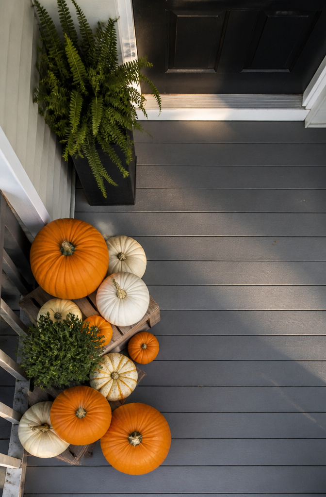 7 Front Porch Fall Decoration Ideas for 2026 11 Stacked pumpkins and lanterns arranged on a small front porch.