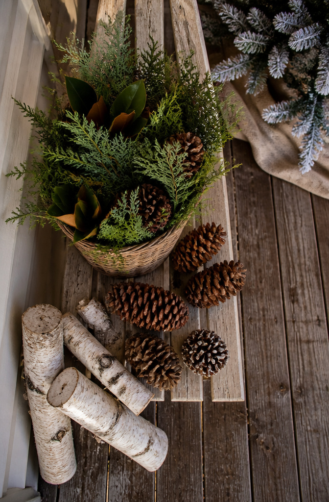 Baskets of greenery and pinecones on a porch.