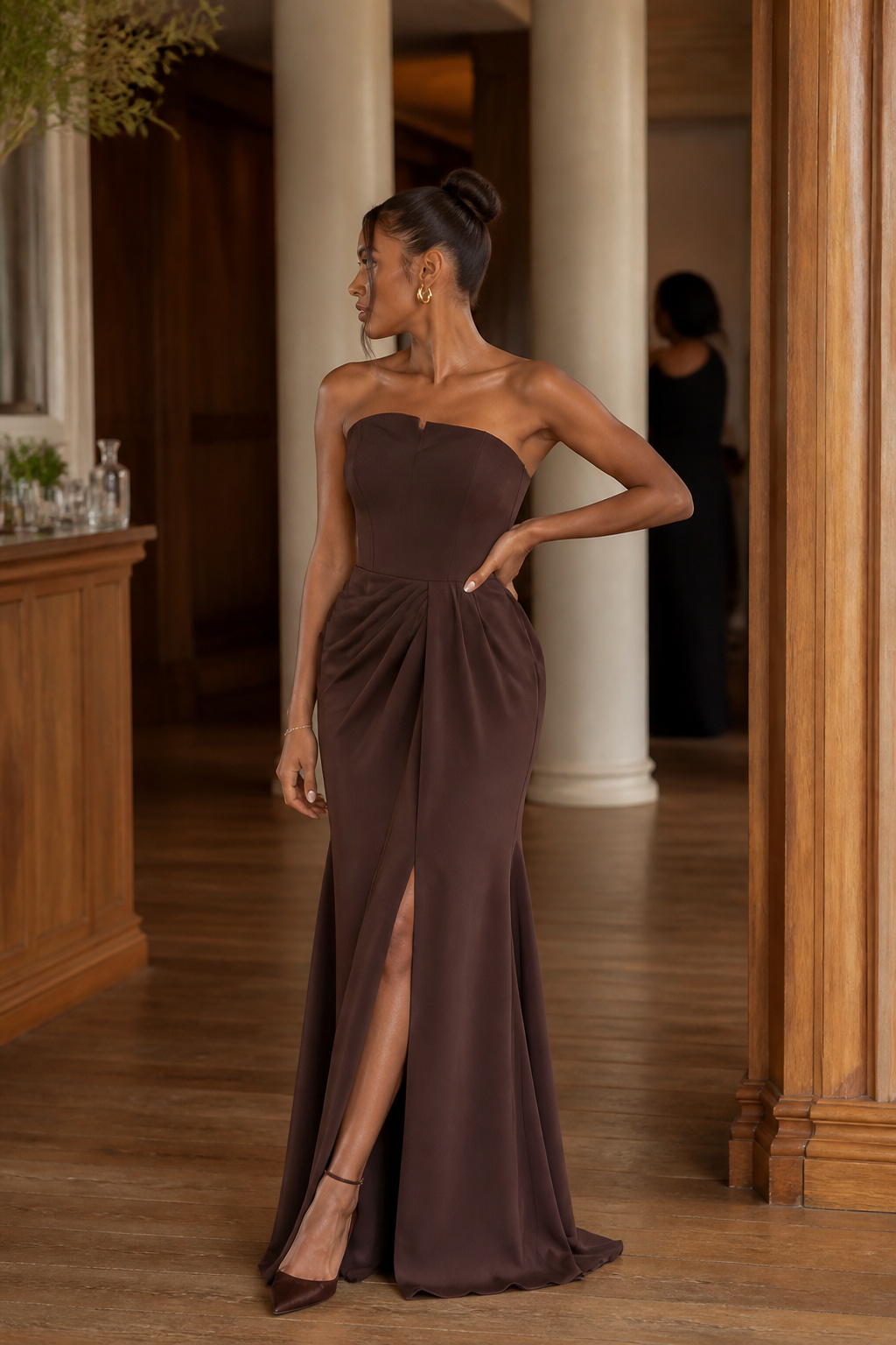 Model in Vesper Kaffeebraun dress against neutral-toned columns.