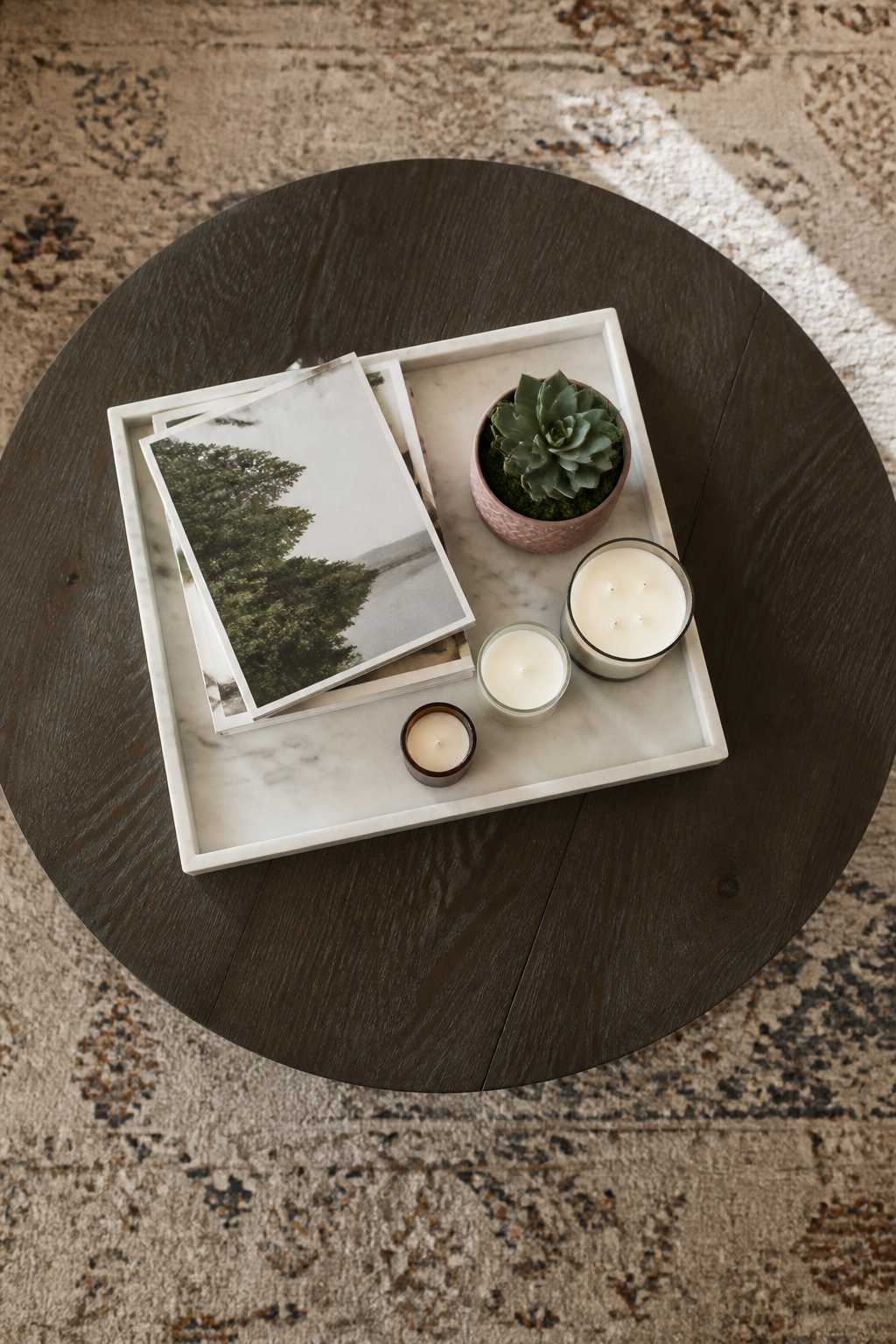 A coffee table with a tray holding candles and remotes.