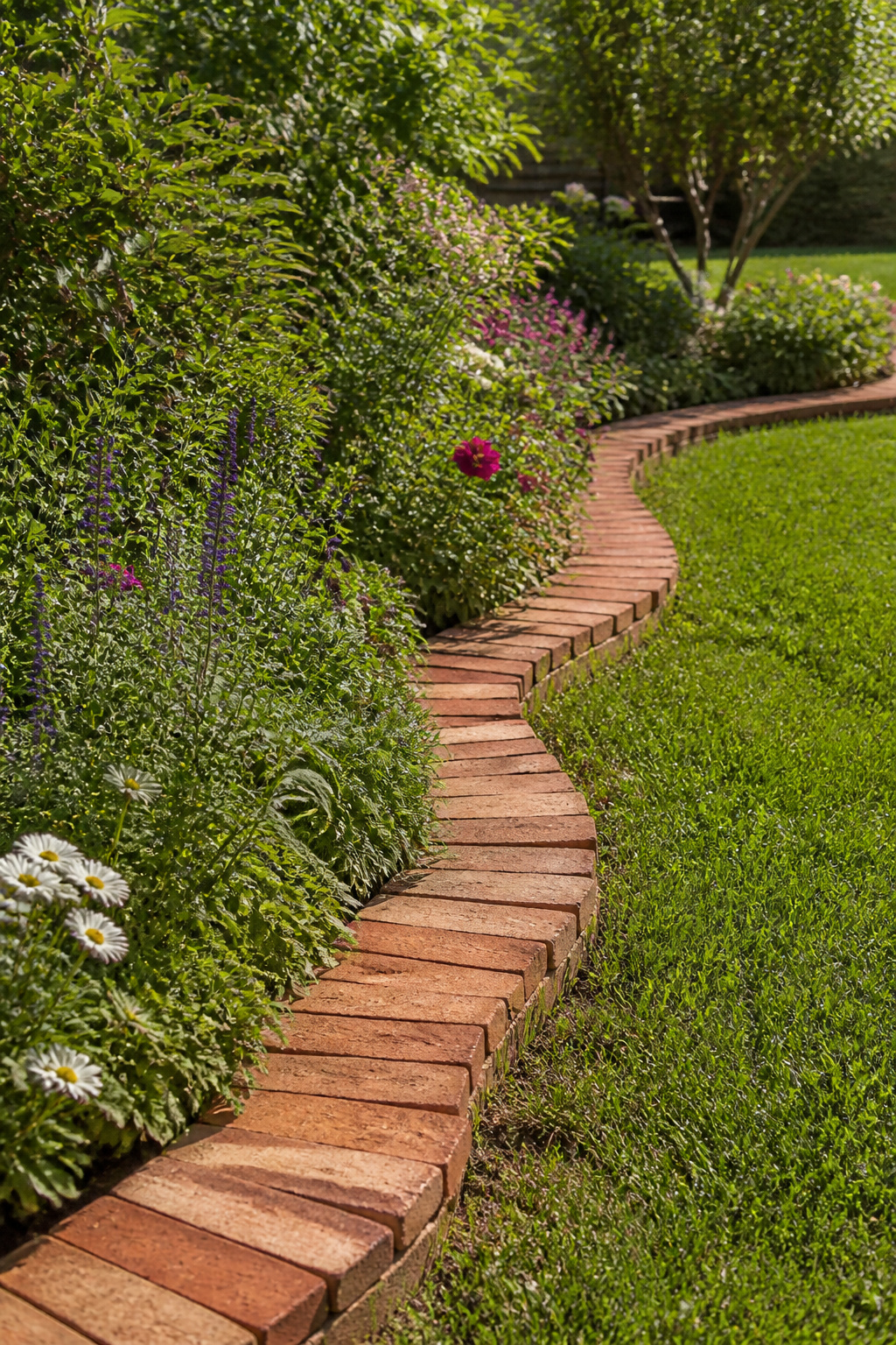 23 Brick and Rock Edging Ideas for Garden Borders (2026) 5 Wavy brick edging along the edge of a flowerbed.
