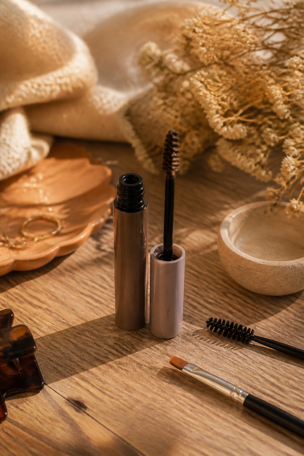 Natural brow gel against a rustic wooden background with makeup tools.