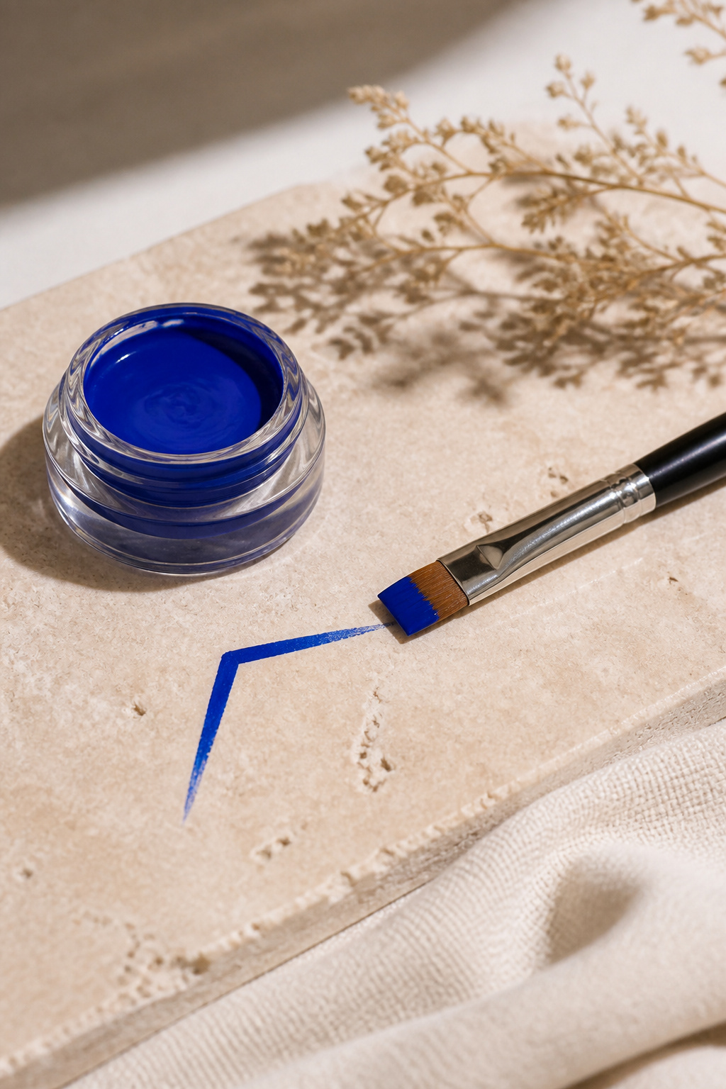 Sleek gel pot of cobalt eyeliner on a neutral backdrop.