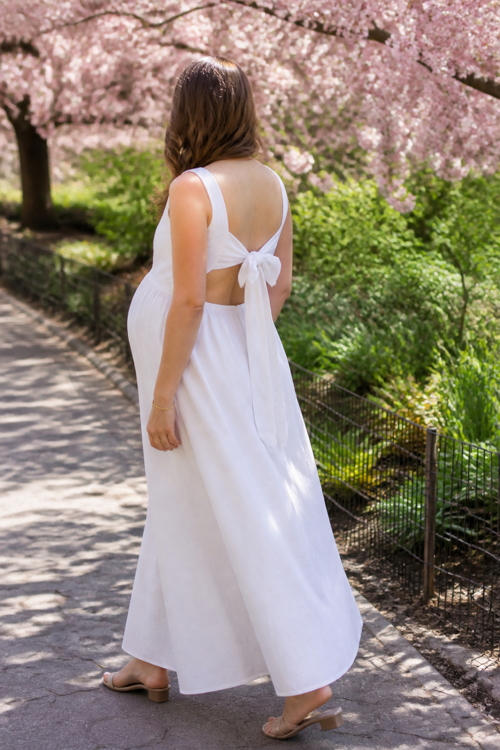A model wearing a maxi dress with a cutout bow back in a park.