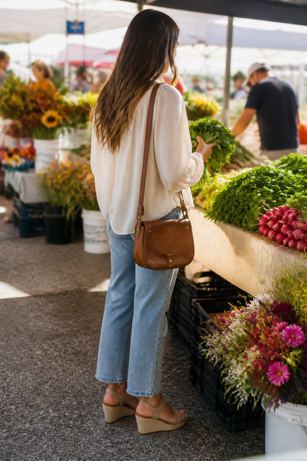 Woman wearing a neutral blouse and relaxed jeans in a market.
