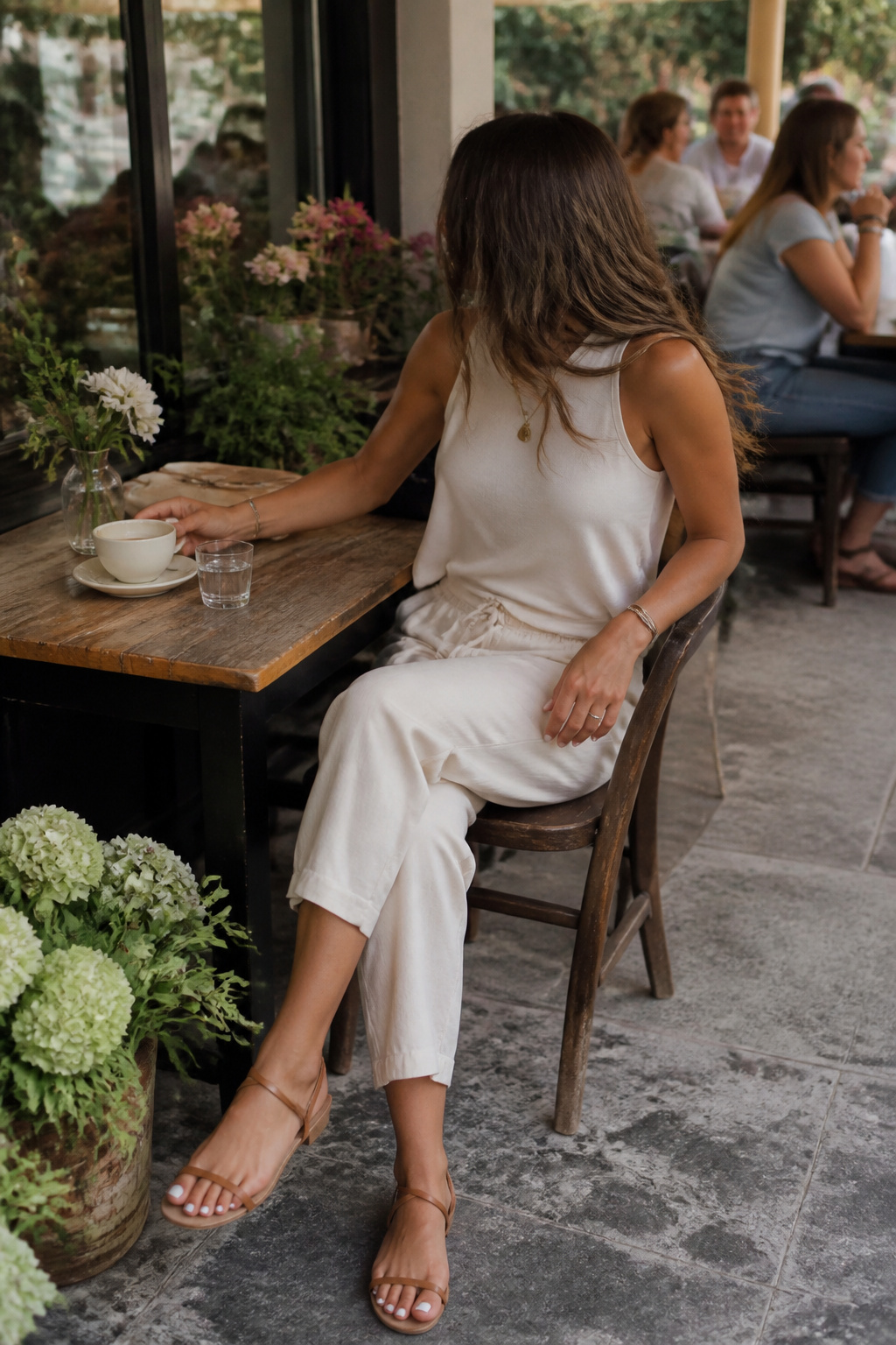 Woman in a sleeveless top and linen pants at a café.