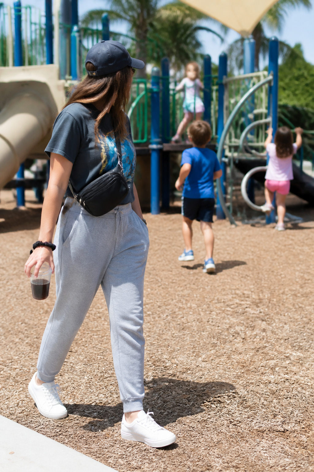 Woman in athleisure pants and a graphic tee at a playground.