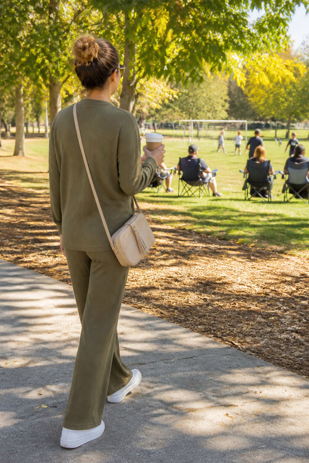 Woman wearing olive lounge set and white sneakers in a park.