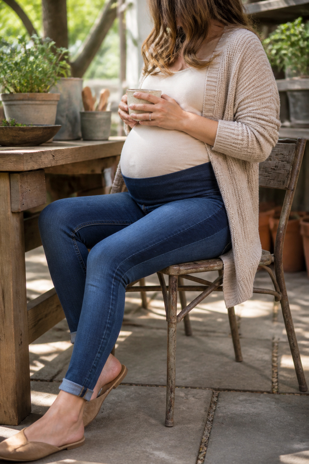 Pregnant woman sitting in maternity skinny jeans at an outdoor café.