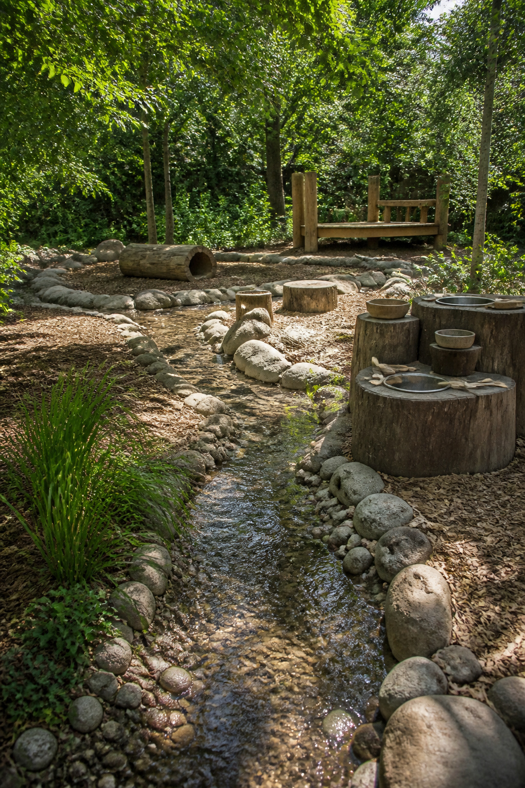 A gentle stream flowing through a natural playground area.