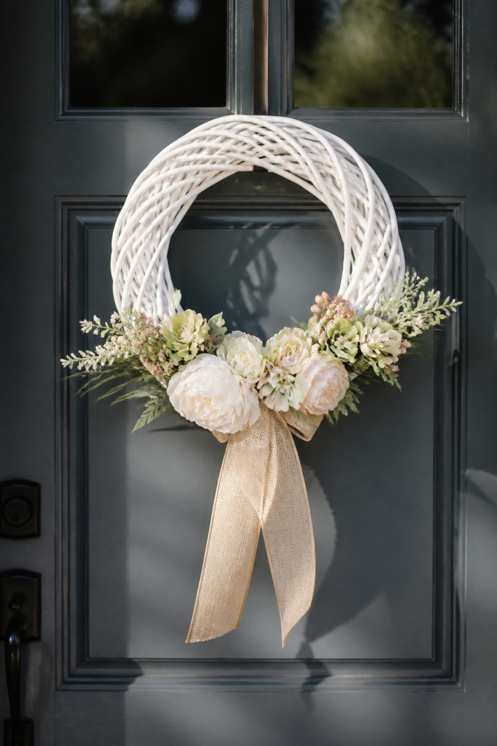 White-painted grapevine wreath decorated with flowers.