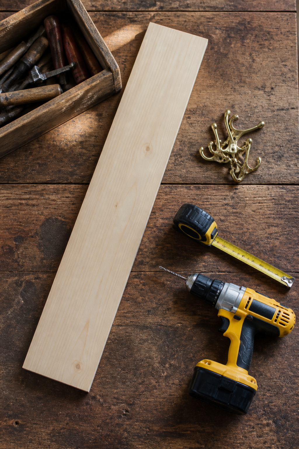 A 1x6 board and brass hooks laid out for a coat rack project.