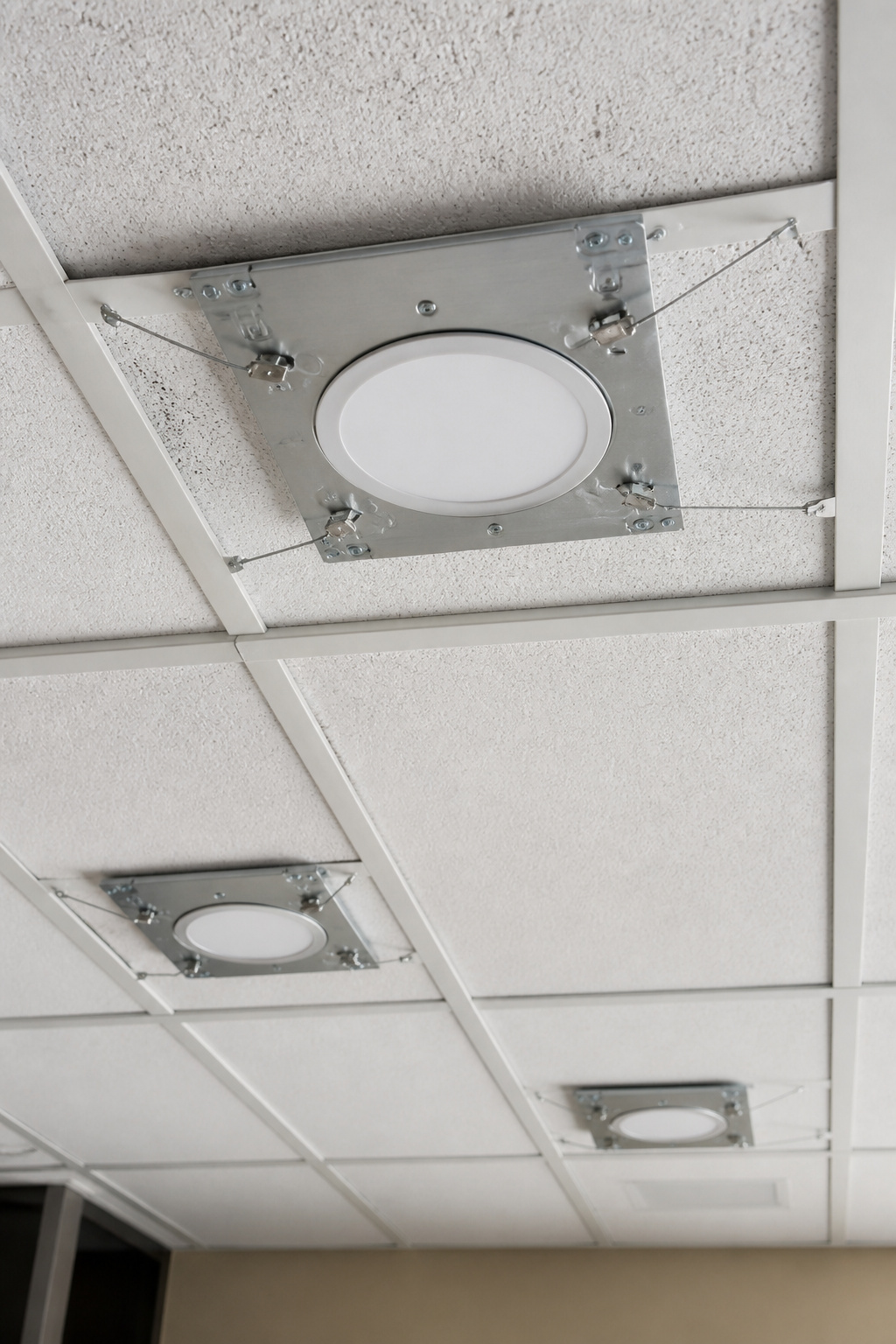 Close-up of wire supports attached to a T-grid for LED fixtures.