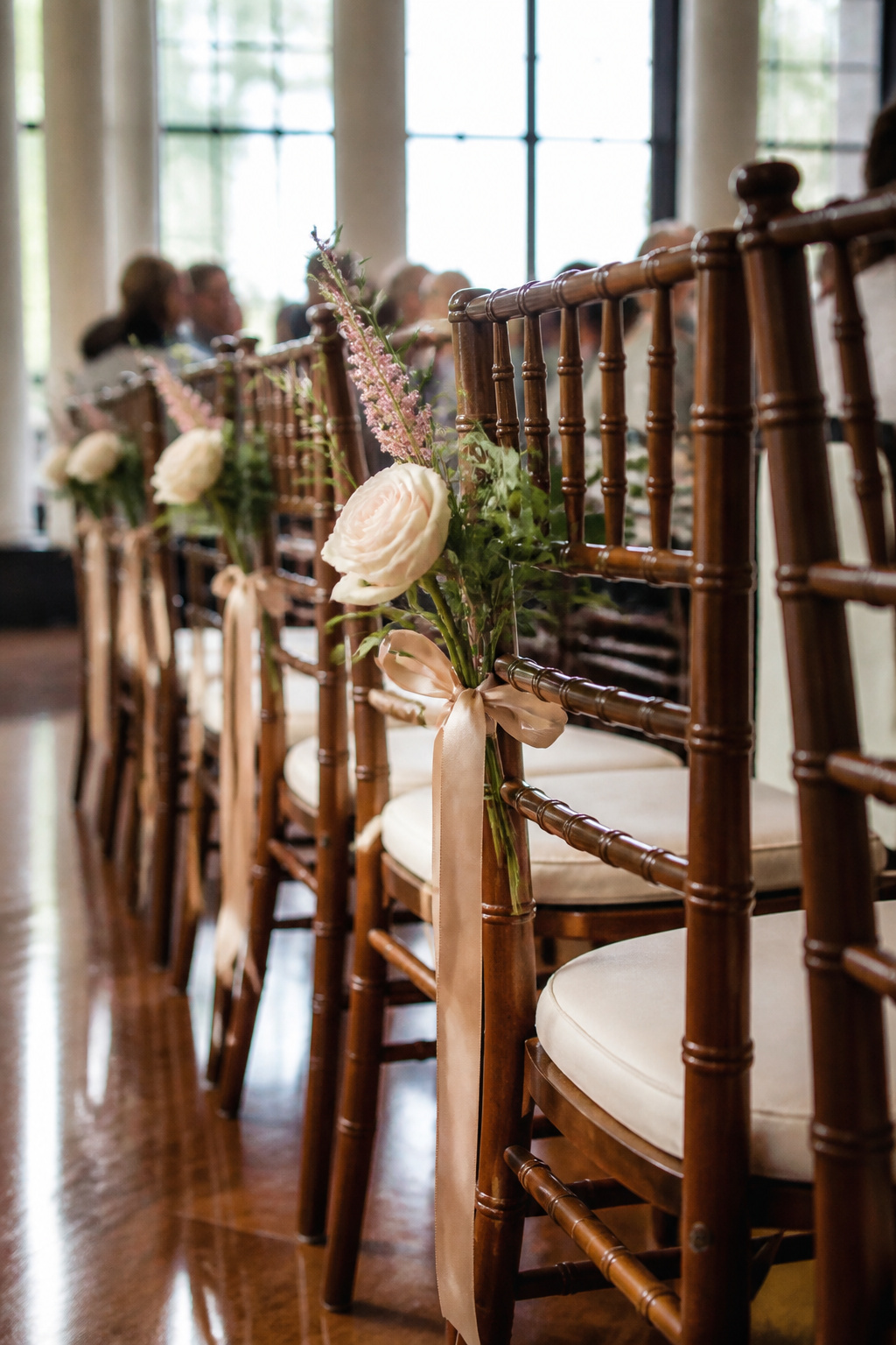 Small flower arrangements attached to the backs of chairs.