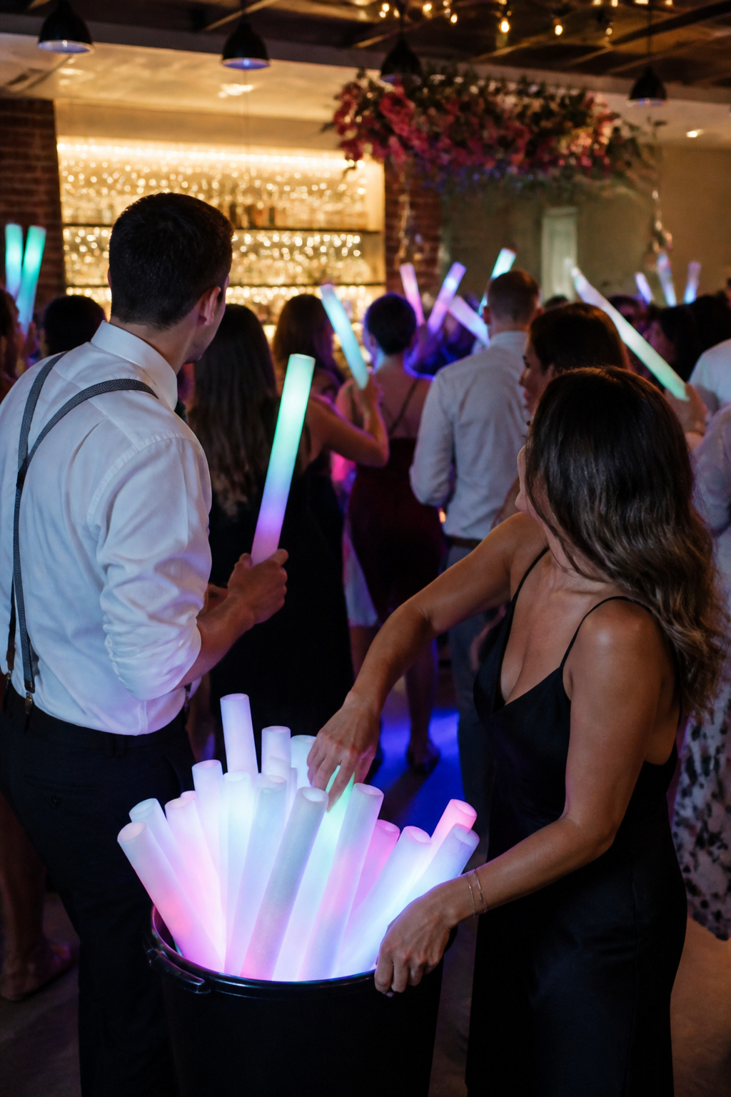 Guests holding glow sticks while dancing at a wedding.