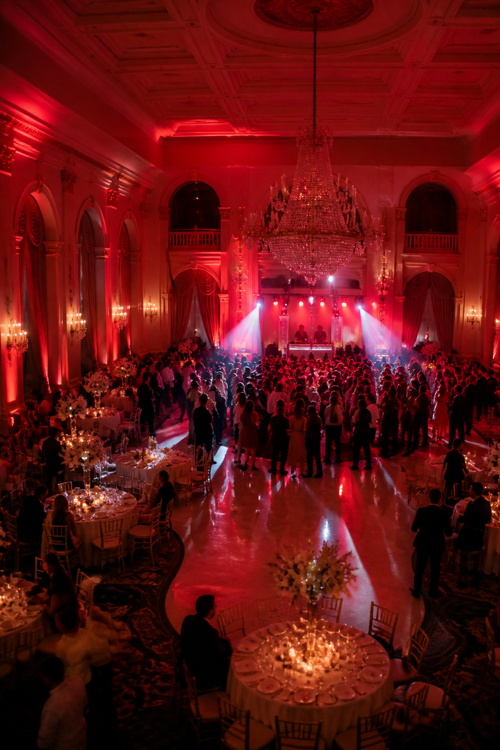 Guests dancing under red lighting at a wedding reception.