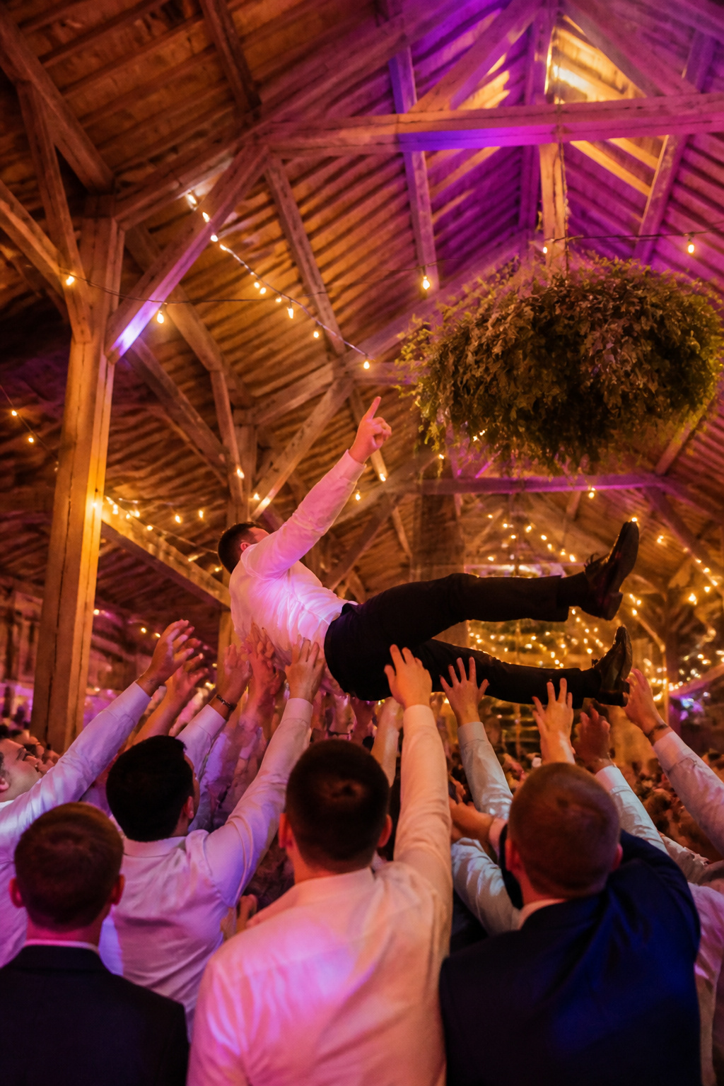 Guests participating in crowd surfing at a wedding reception.