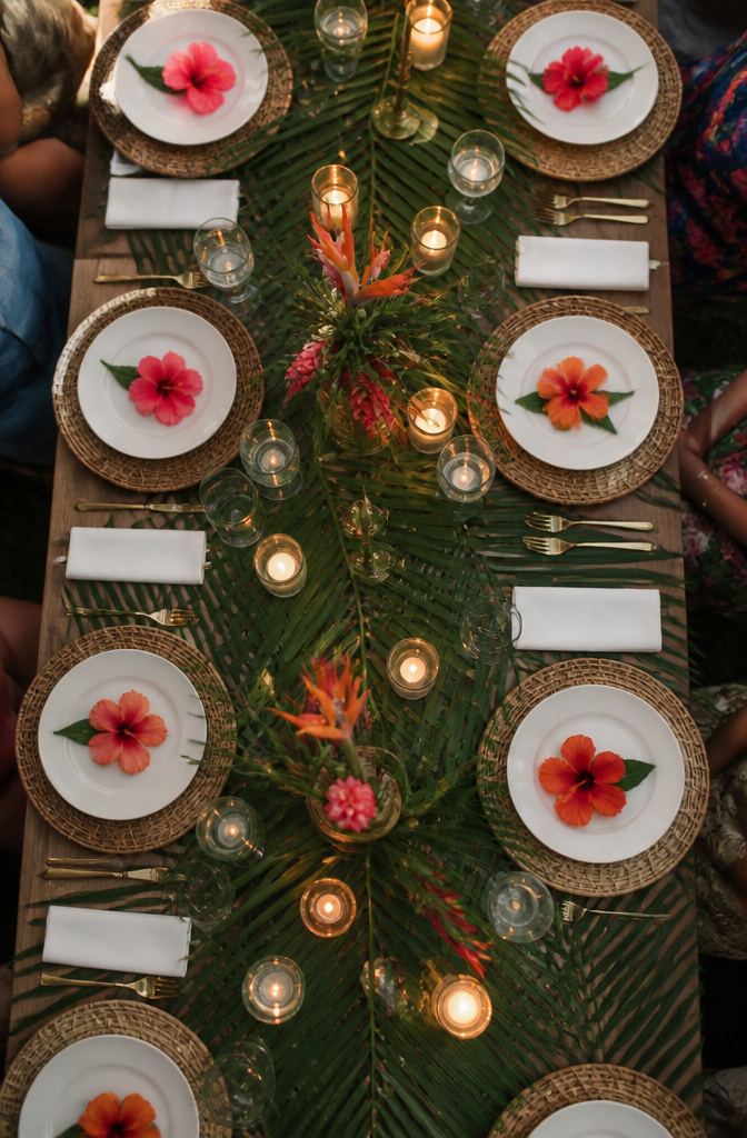 20 Wedding Ideas for a Memorable 2026 Celebration 5 A table setting with palm leaves, rattan chargers, and a hibiscus flower.
