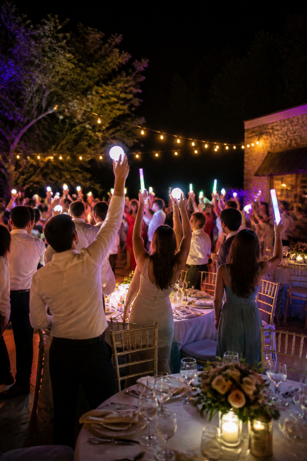 Guests holding glow sticks during a wedding dance party.