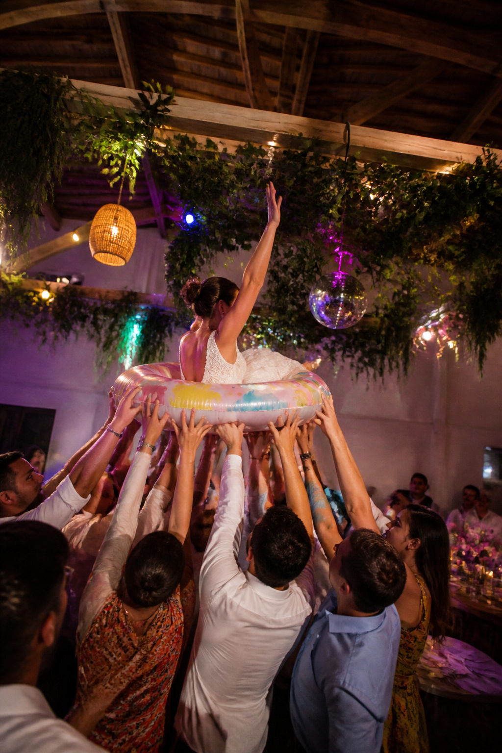 Guests crowd surfing on inflatable pool floats at a wedding.