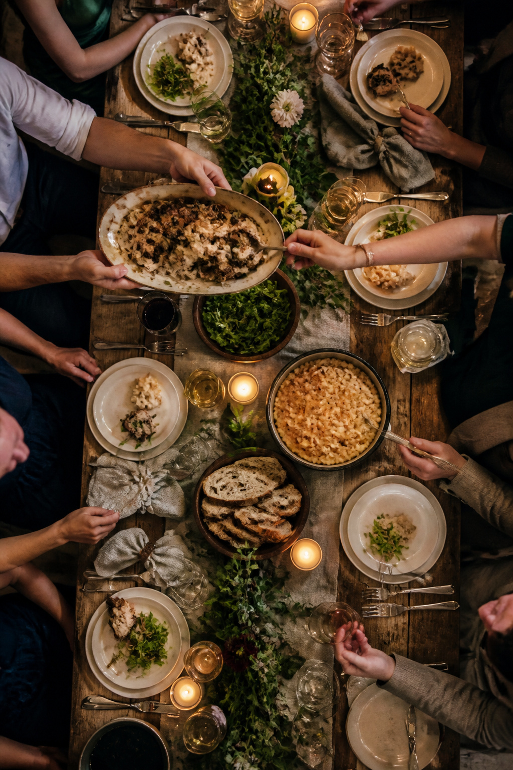 Guests at a family-style dining table sharing platters of food.