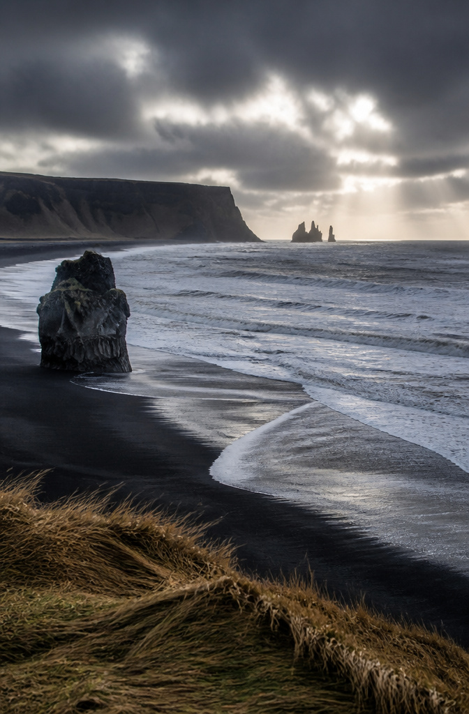 A varied landscape in Iceland showing black sand beaches and rugged terrain.