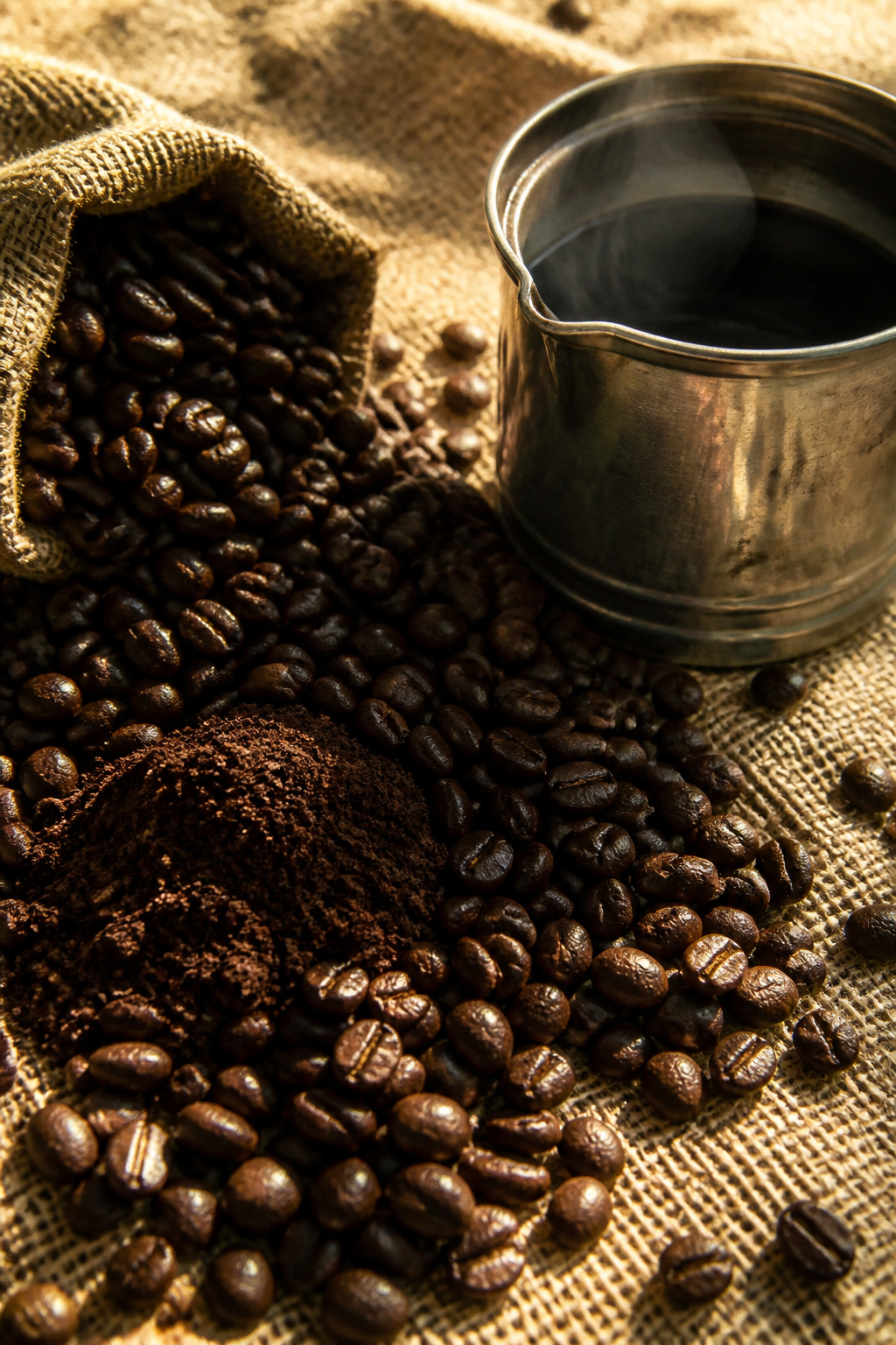 Close-up of coffee beans and ground coffee on burlap.