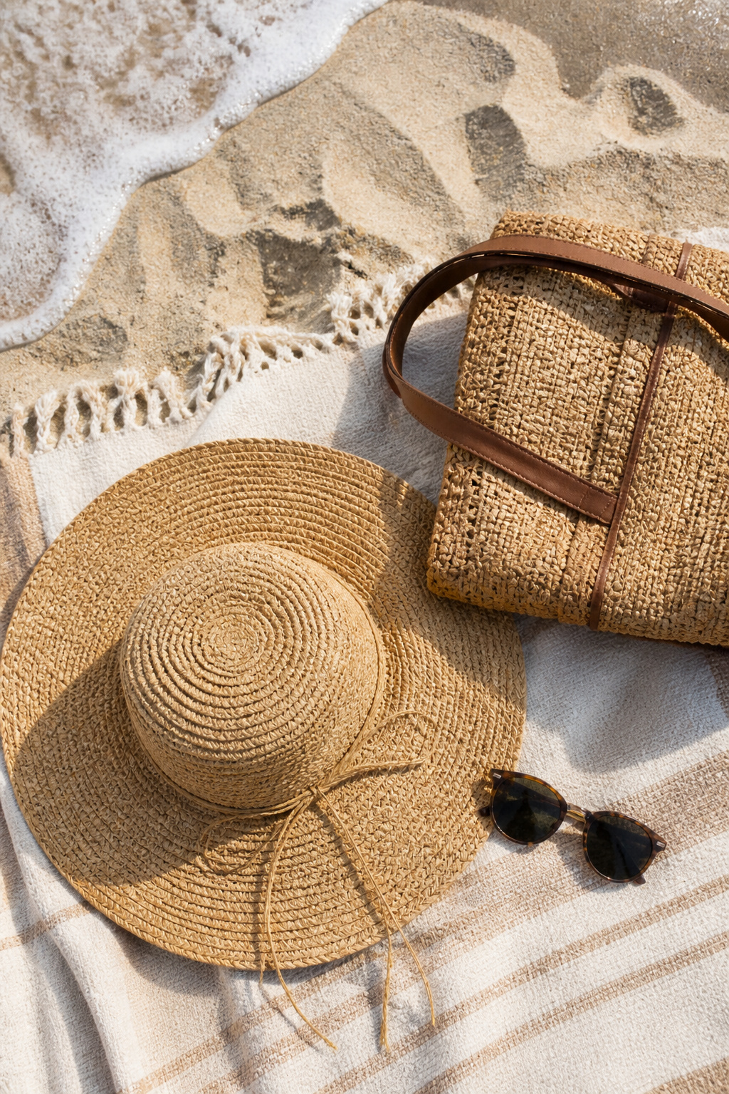Straw hat and sunglasses resting on a beach bag.