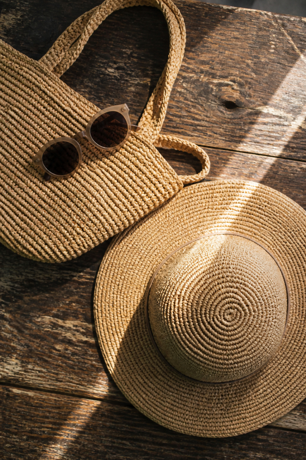 A pair of sunglasses and a straw bag on a table.