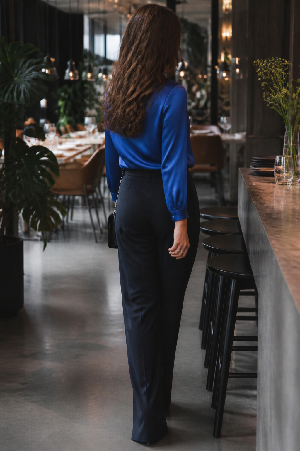 Model wearing a silk blouse with relaxed-fit trousers in a chic setting.