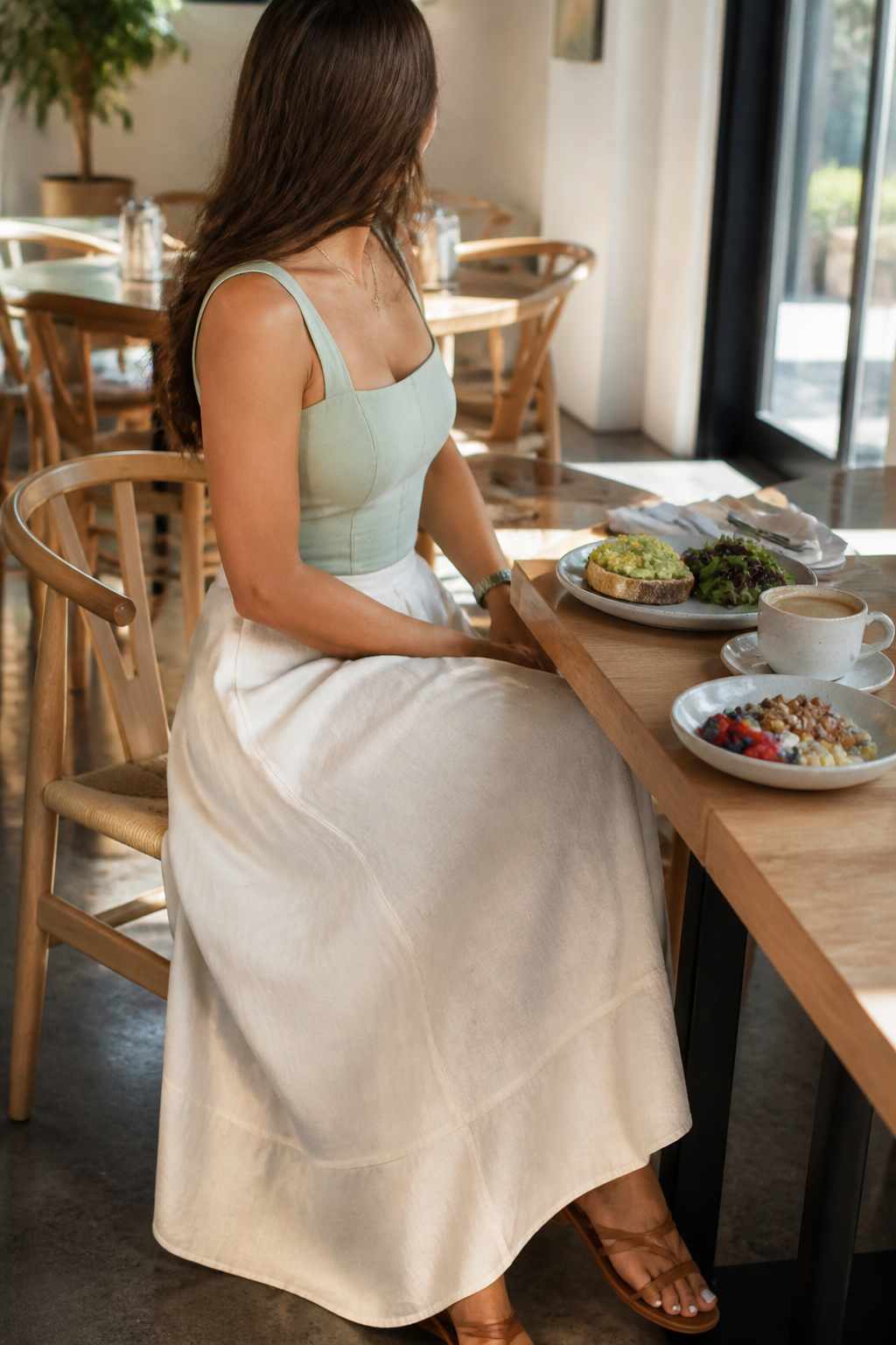 Model seated at a cafe wearing a linen skirt and cotton poplin top.
