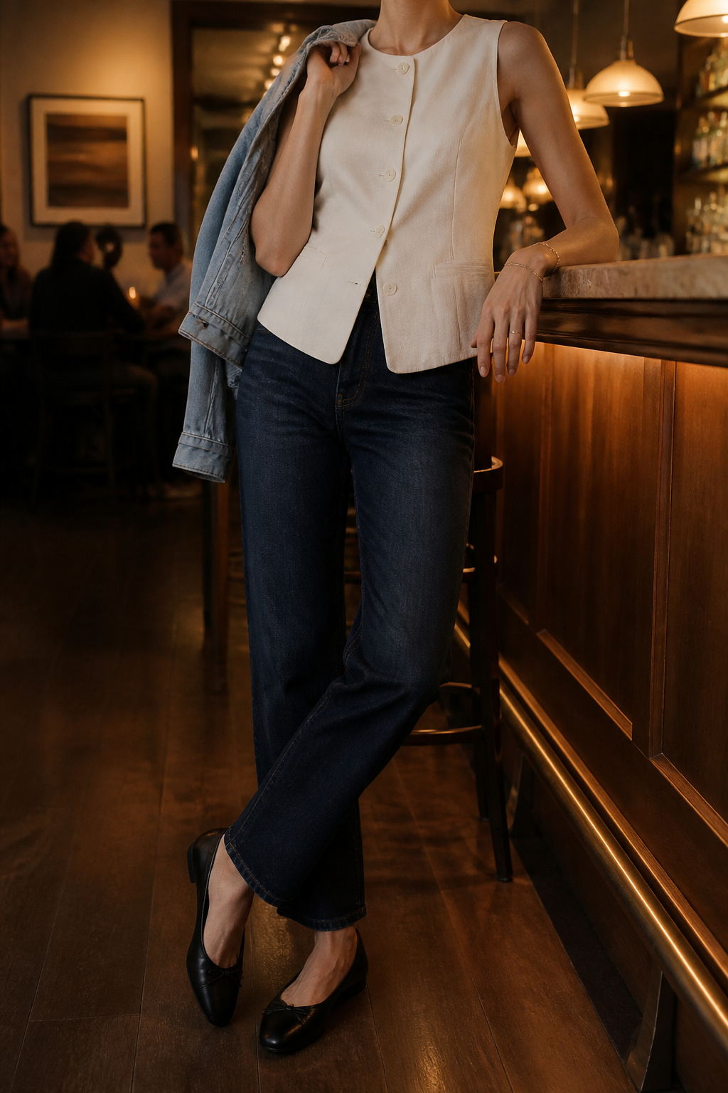 A model in a cutaway vest and dark-wash denim with a denim jacket.