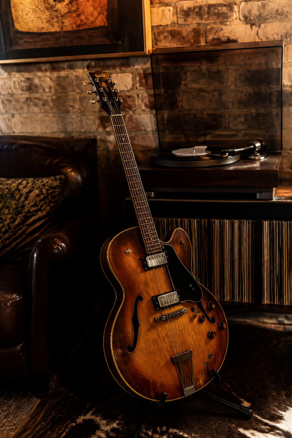 A vintage guitar against a backdrop of an old record player.