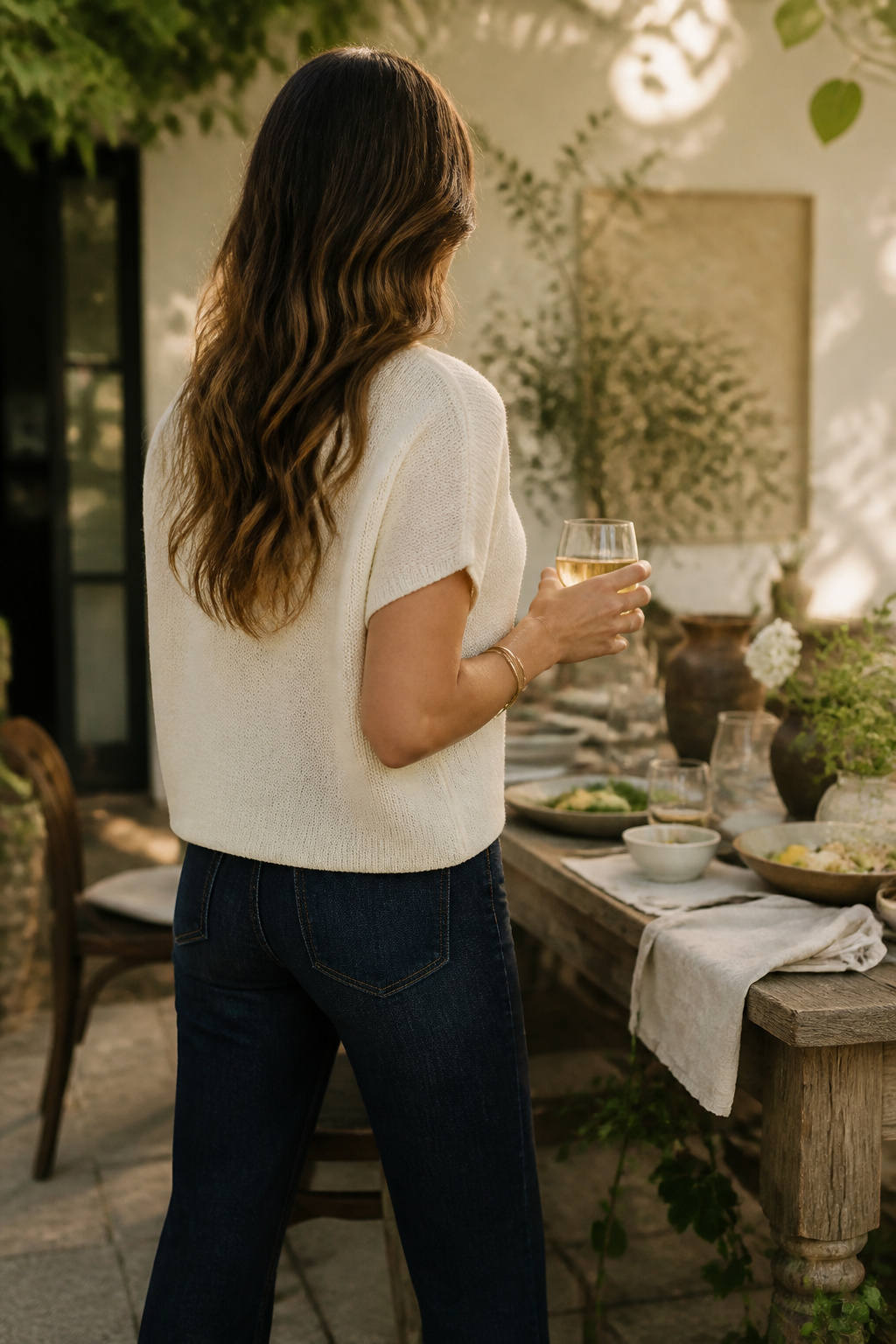 Dark-wash jeans paired with a soft ivory knit top at a dinner party.