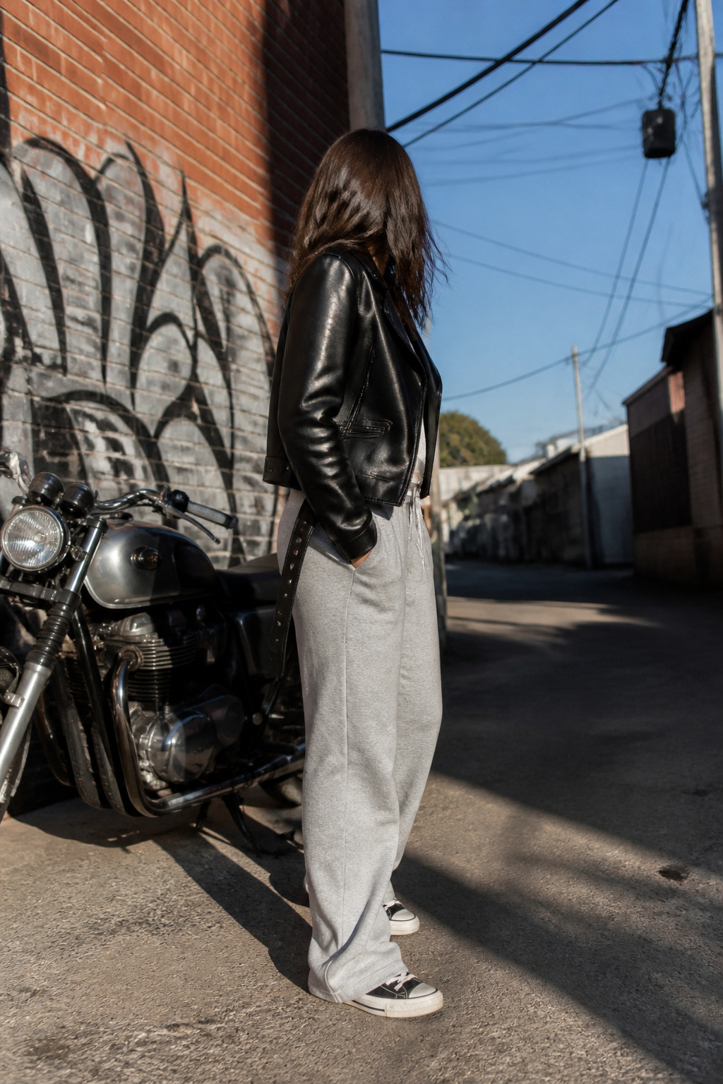 A black leather jacket worn over gray sweatpants.