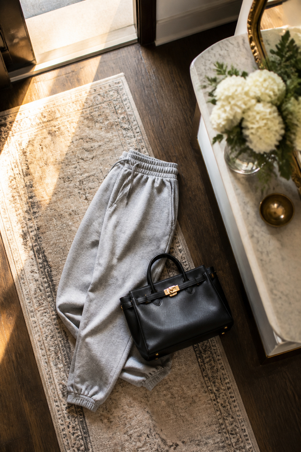 A structured bag and jewelry paired with sweatpants.