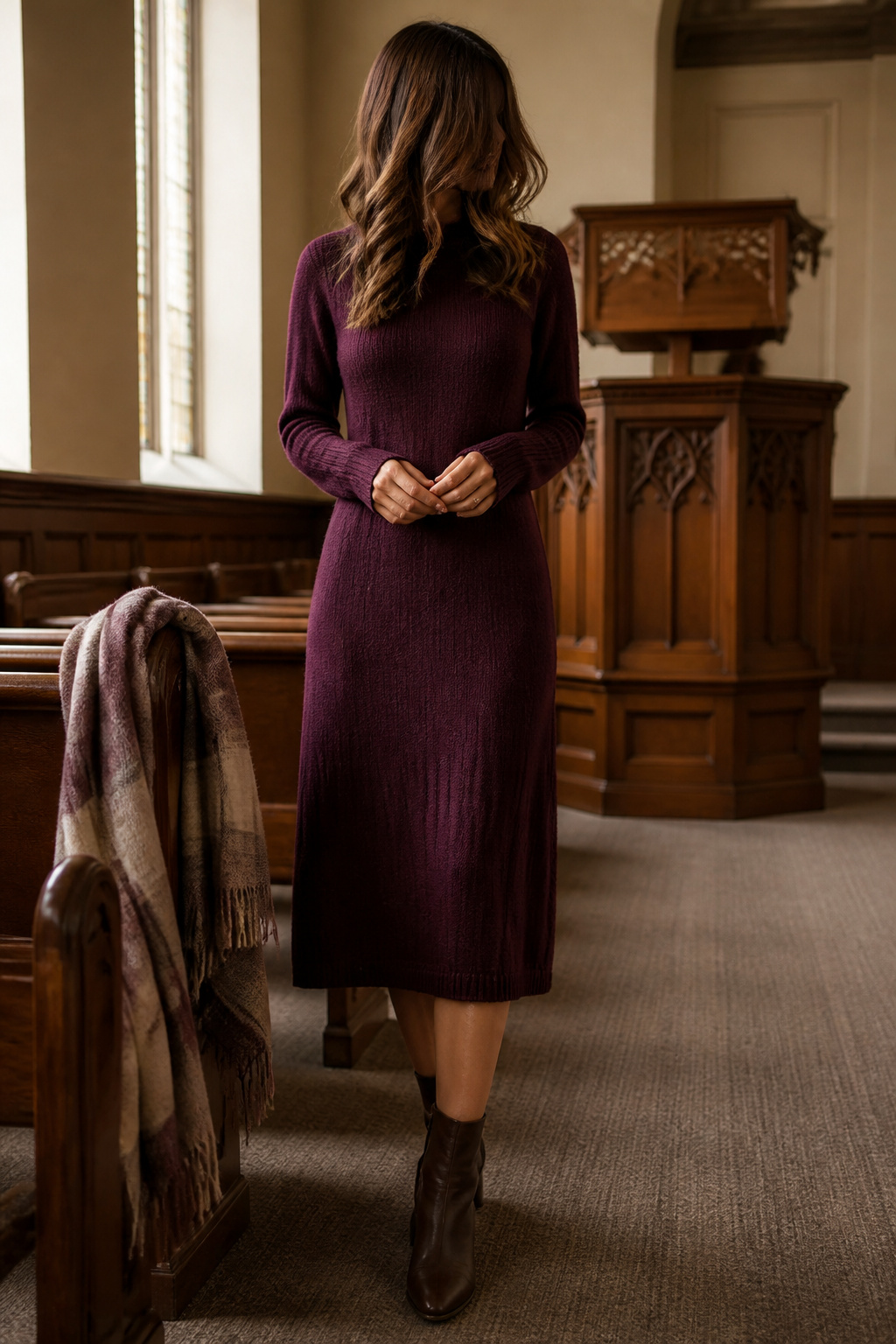 Heavy cable knit sweater dress in camel or ivory worn without a belt.
