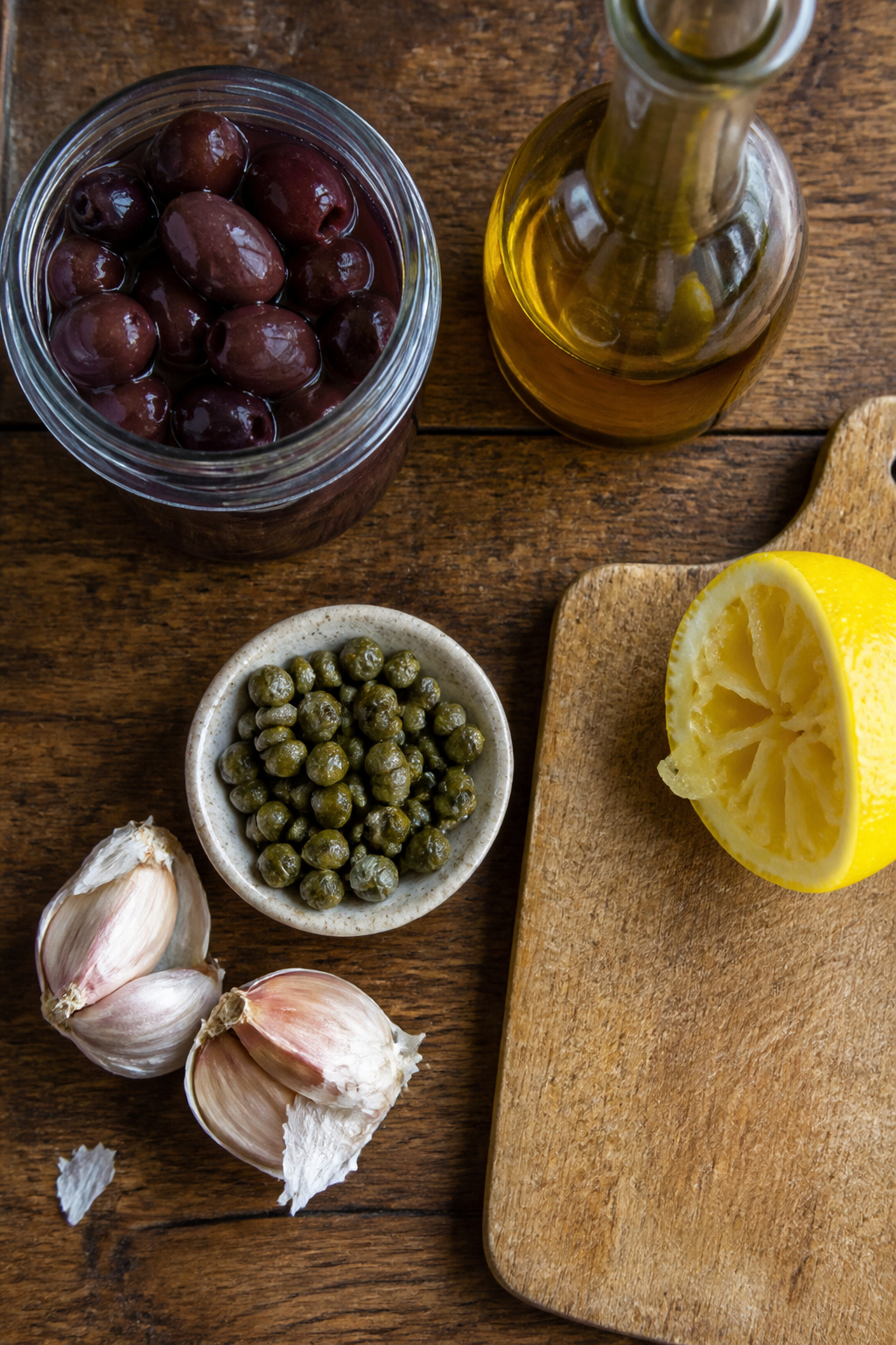 A 7 oz. jar of pitted Kalamata olives on a wooden counter.