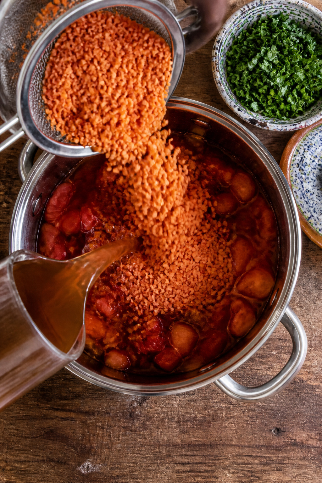 Rinsed red lentils, diced tomatoes, and broth in a pot.