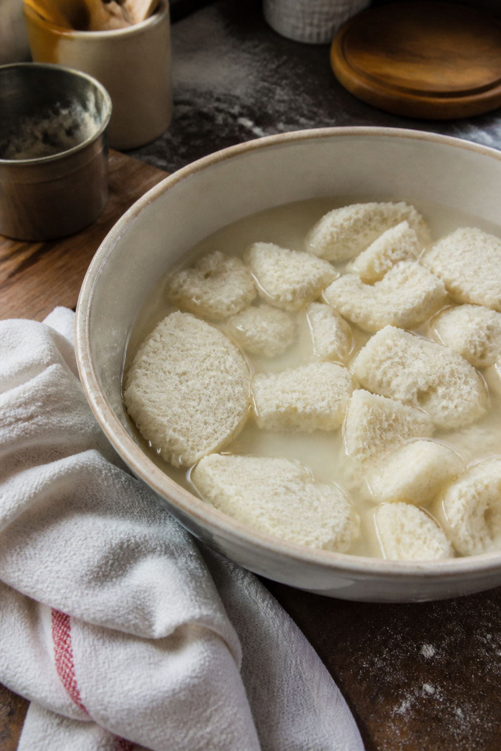 Bowl of day-old white bread pieces submerged in water.