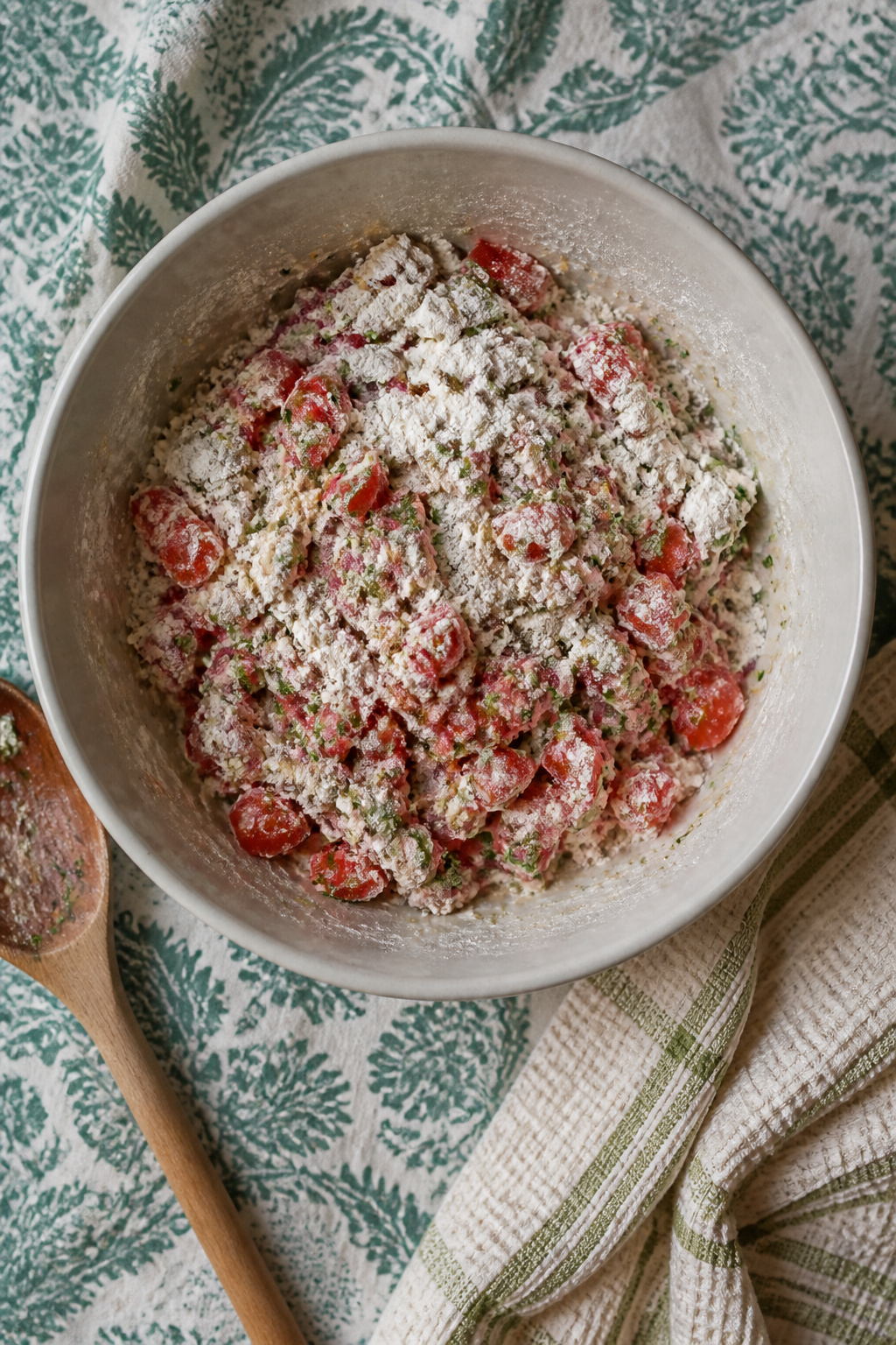 A bowl filled with tomato batter, chopped herbs, and onion.