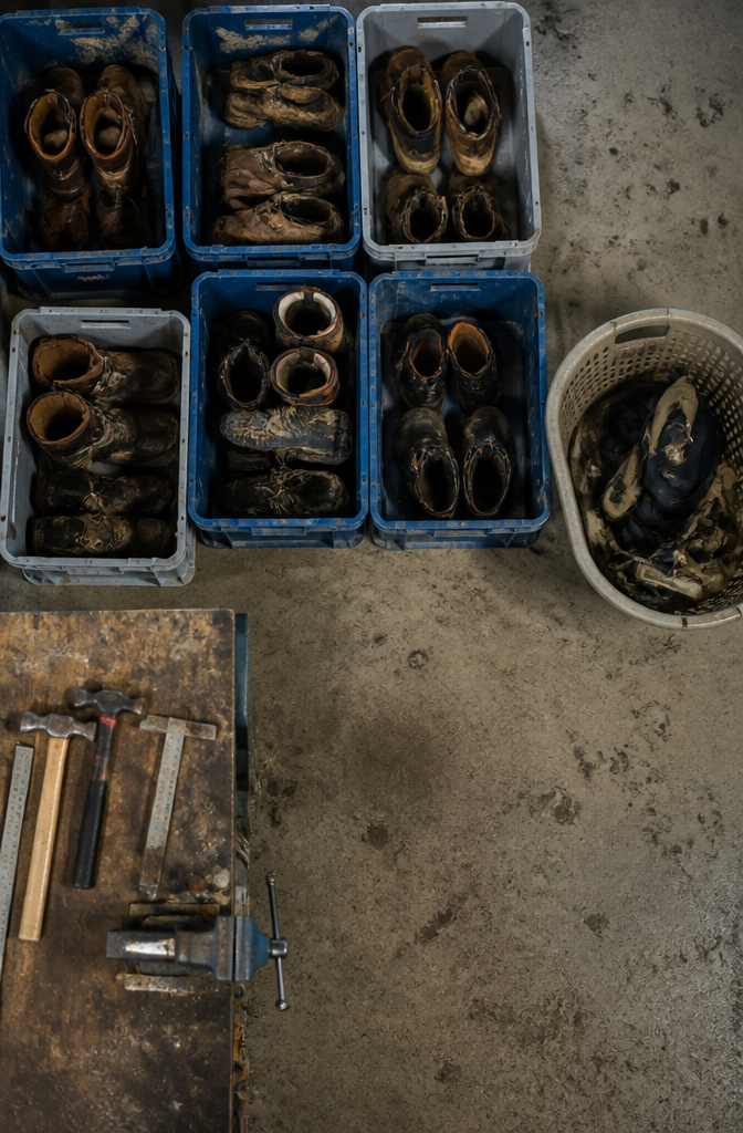 Plastic crates storing various pairs of heavy-duty work boots.