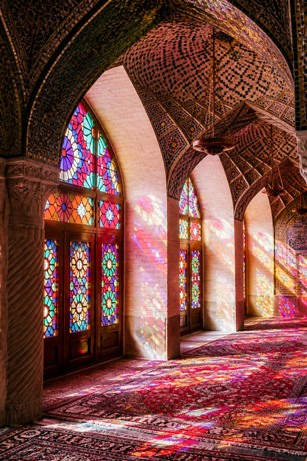 Stained glass windows of Nasir al-Mulk Mosque creating a pink-hued prayer hall.