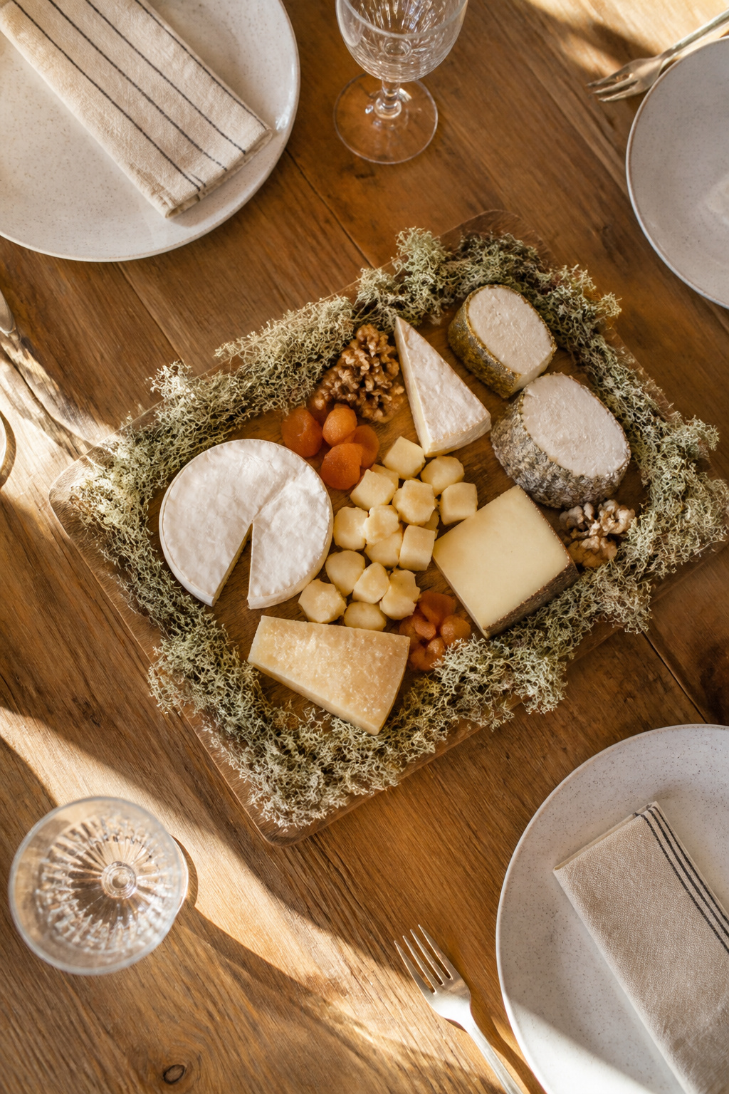 25 Easter Table Settings for 2026 Spring Gatherings 17 Wooden serving board edged with moss holding cheese.