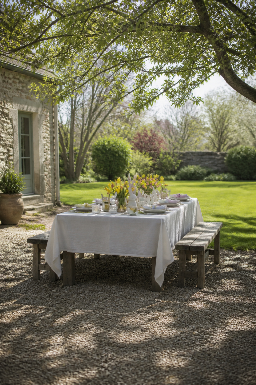 25 Easter Table Settings for 2026 Spring Gatherings 28 Tablecloth secured with glass votive holders on an outdoor table.