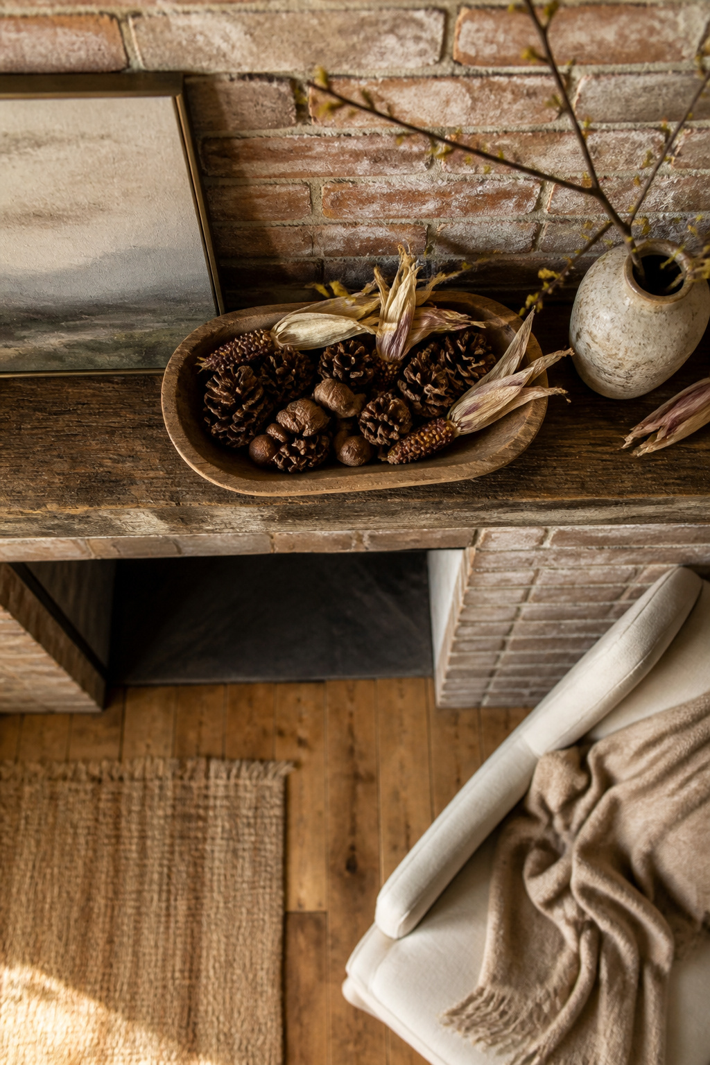 11 Fall Mantel Decoration Ideas for a Styled Hearth 5 Pinecones and corn husks arranged on a wooden bowl on a mantel.