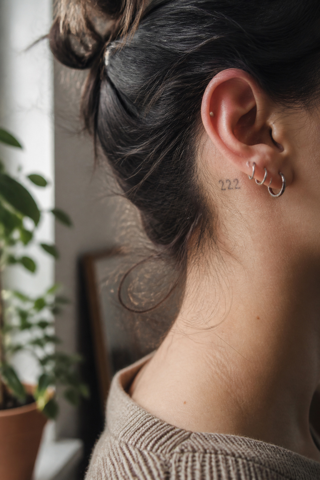 Side profile showing a '222' tattoo inked behind the ear.