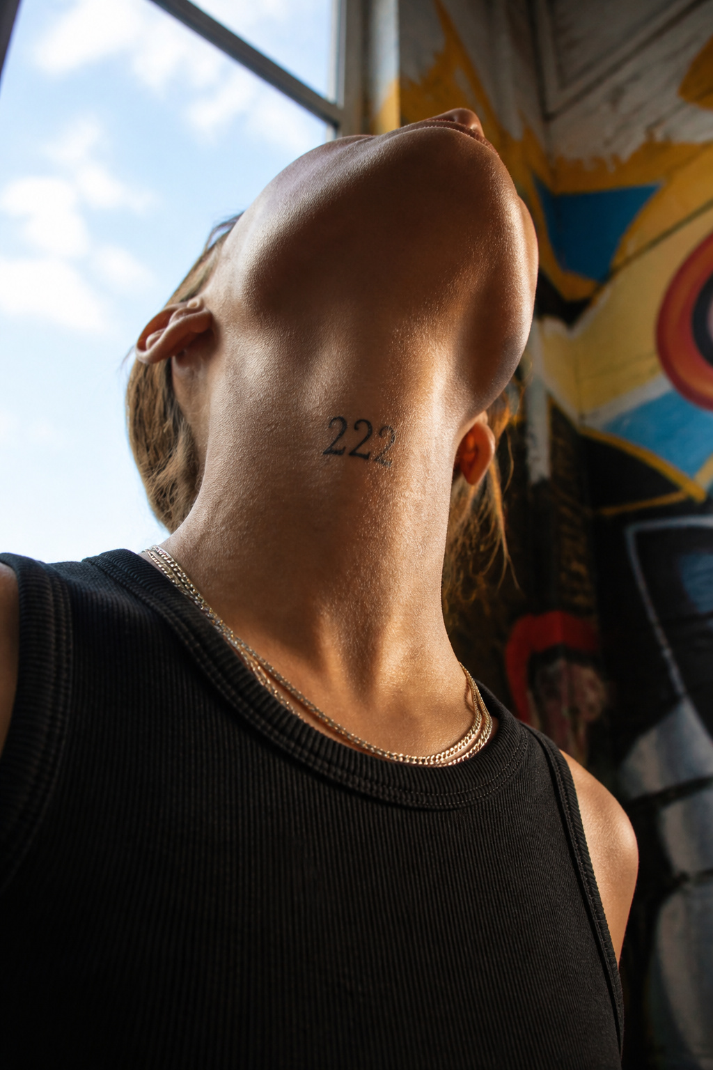 A '222' tattoo prominently displayed on the neck.