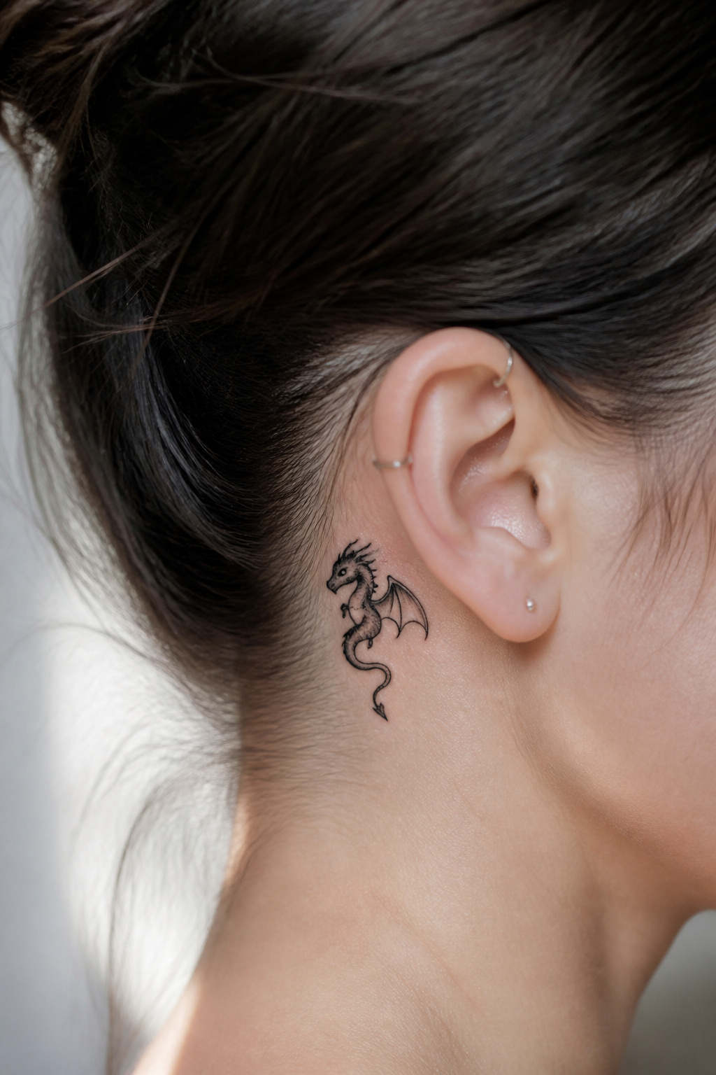 Stylized mini dragon tattoo behind the ear.