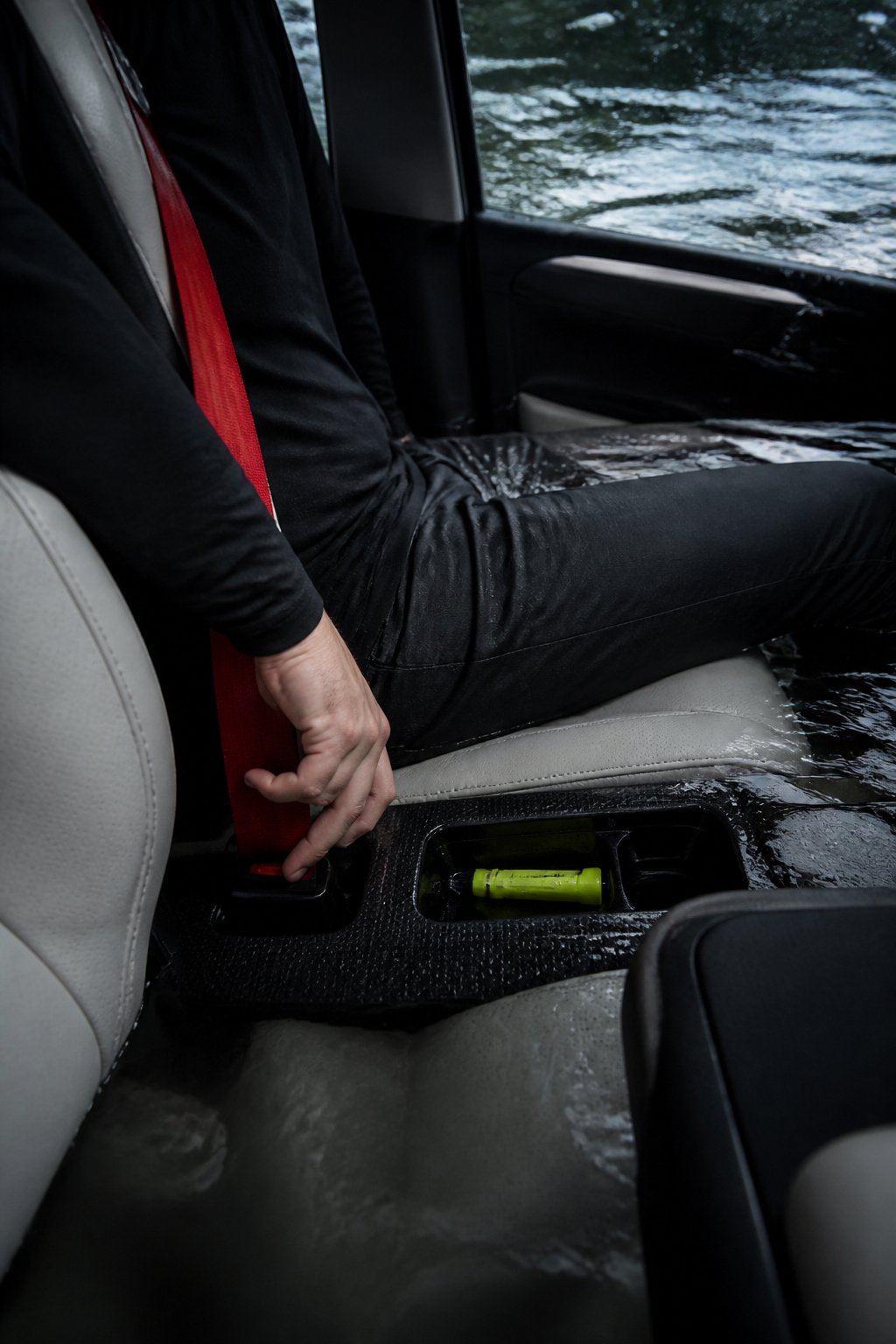 How to Escape a Sinking Car: 5 Steps That Save Lives in 2026 2 A hand reaching for a seatbelt release against a wet car interior.